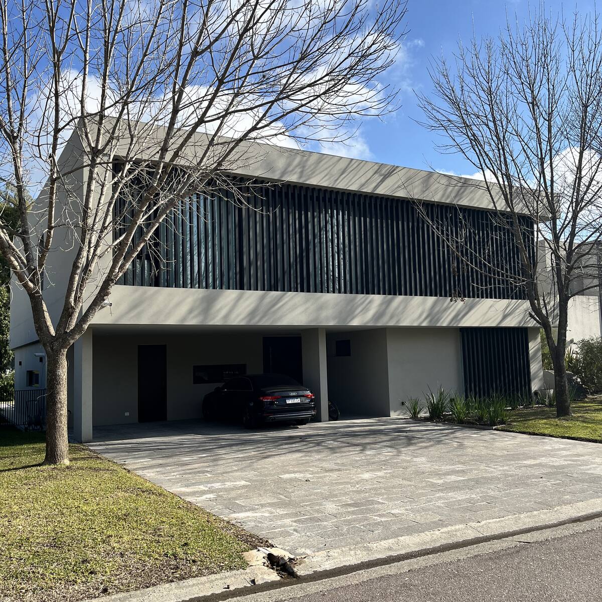 Frente de una casa moderna construida por ARK+ en Puertos del Lago
