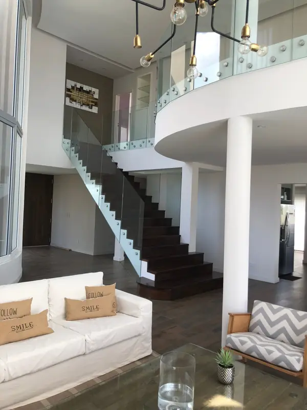 Escalera con baranda de vidrio y balcón interior curvo